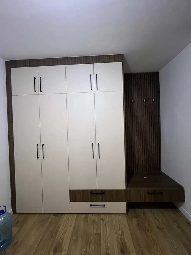 Weißer Kleiderschrank mit Holzrahmen und angrenzender Garderobe mit Sitzbank