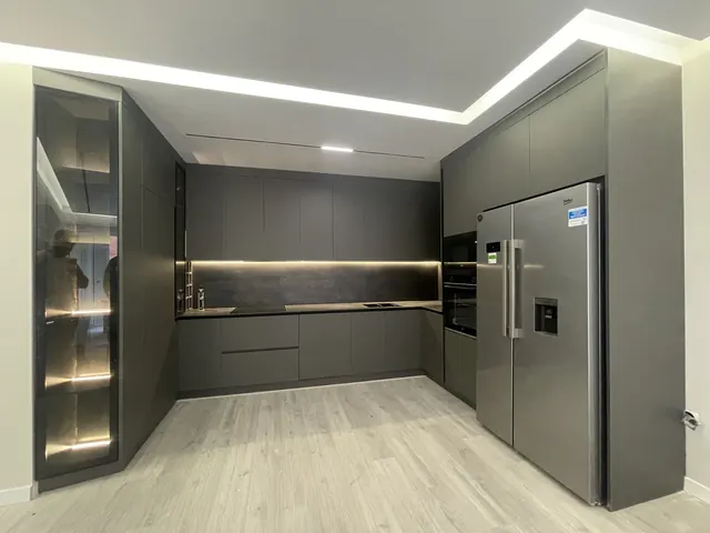 Anthrazitfarbene Küche mit Glasvitrine, beleuchteter Nische und Side-by-Side-Kühlschrank