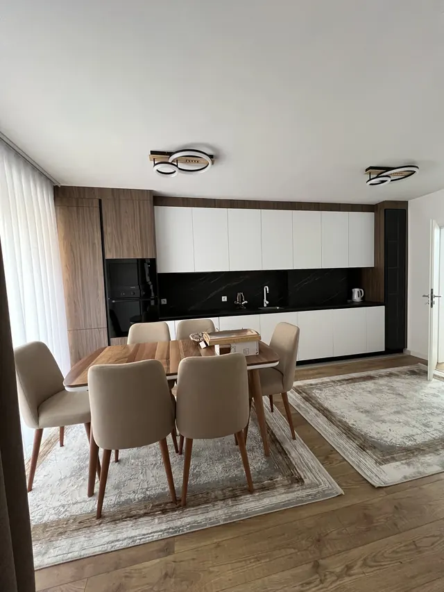 Weiße Küchenzeile mit Holzschränken und Essbereich davor